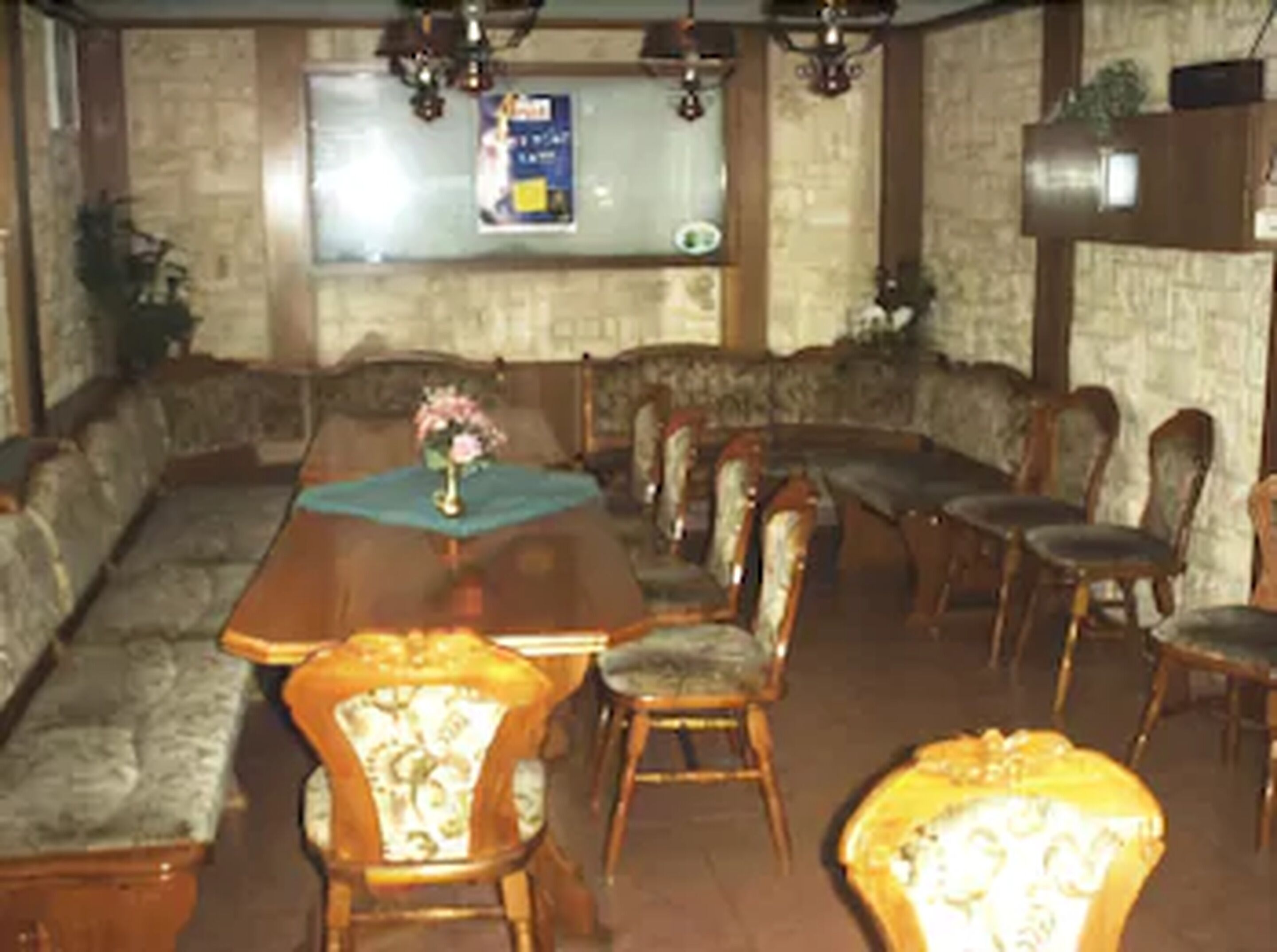 A dining area with a long wooden table, cushioned seating, and a bulletin board on the wall.
