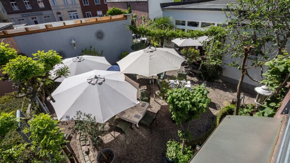 An outdoor patio area with multiple white umbrellas, seating, and potted plants.