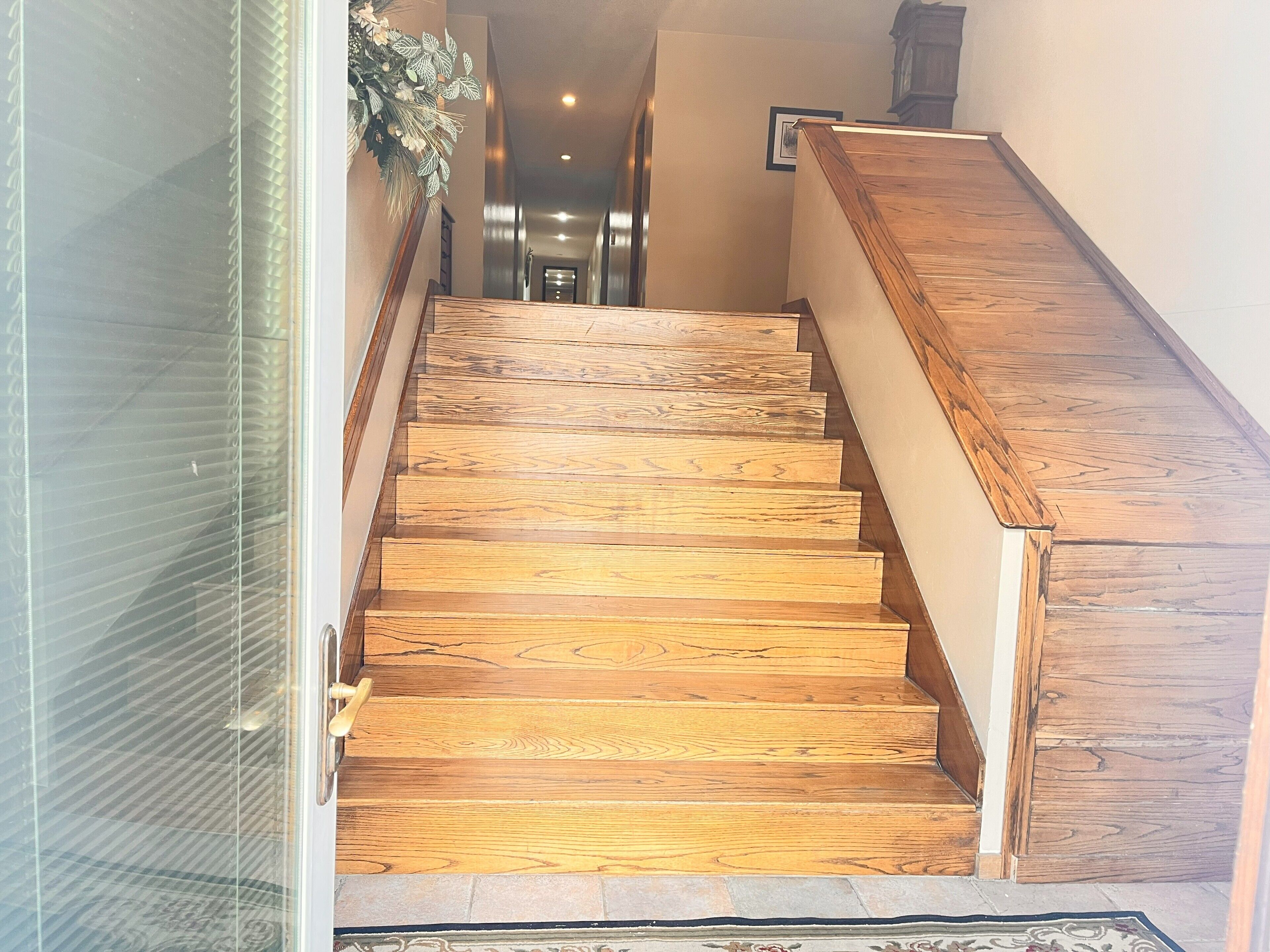 Una escalera de madera con barandilla que da acceso a un espacio interior.