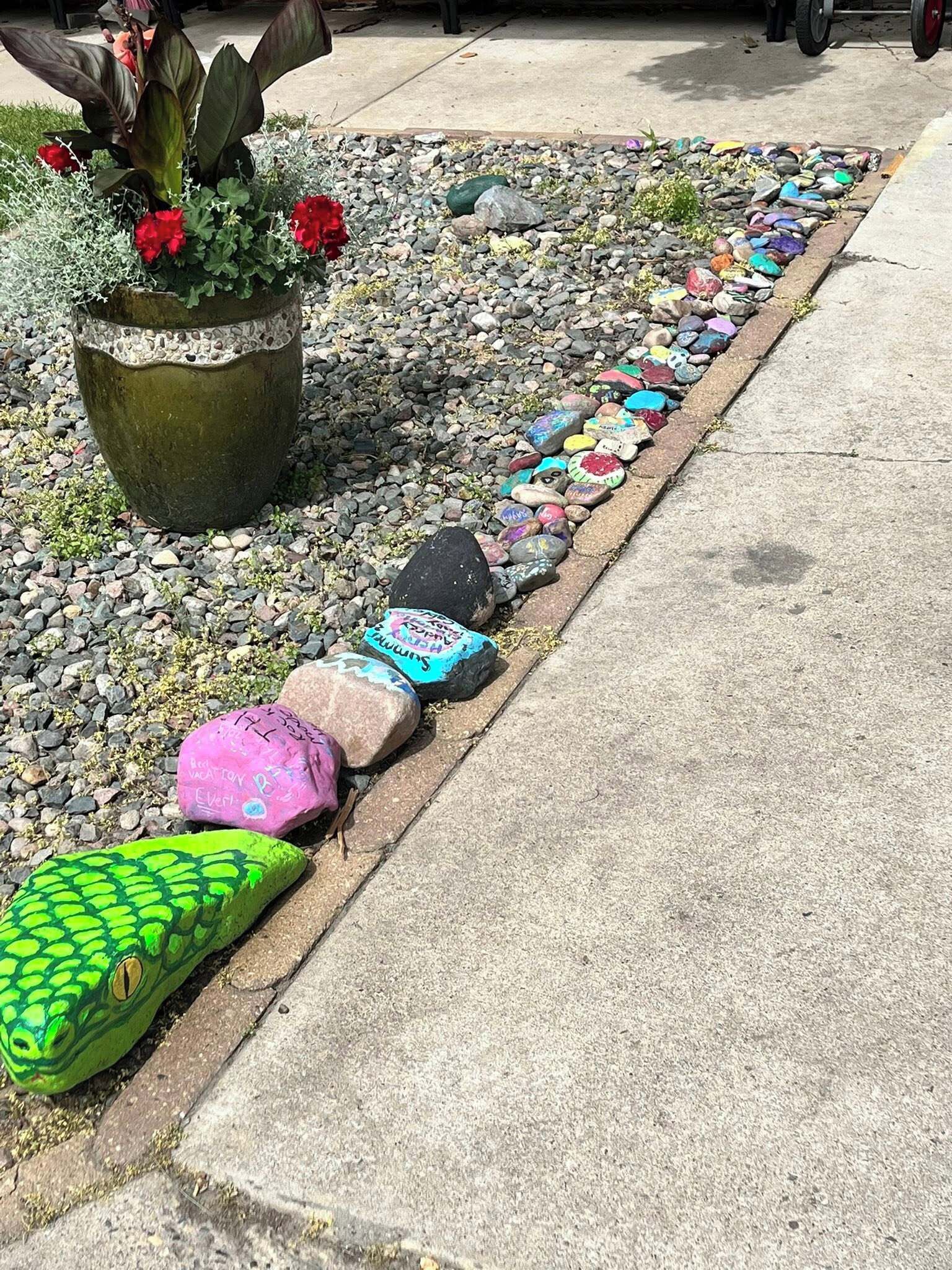 A garden with a variety of plants and a decorative pathway made of painted rocks.