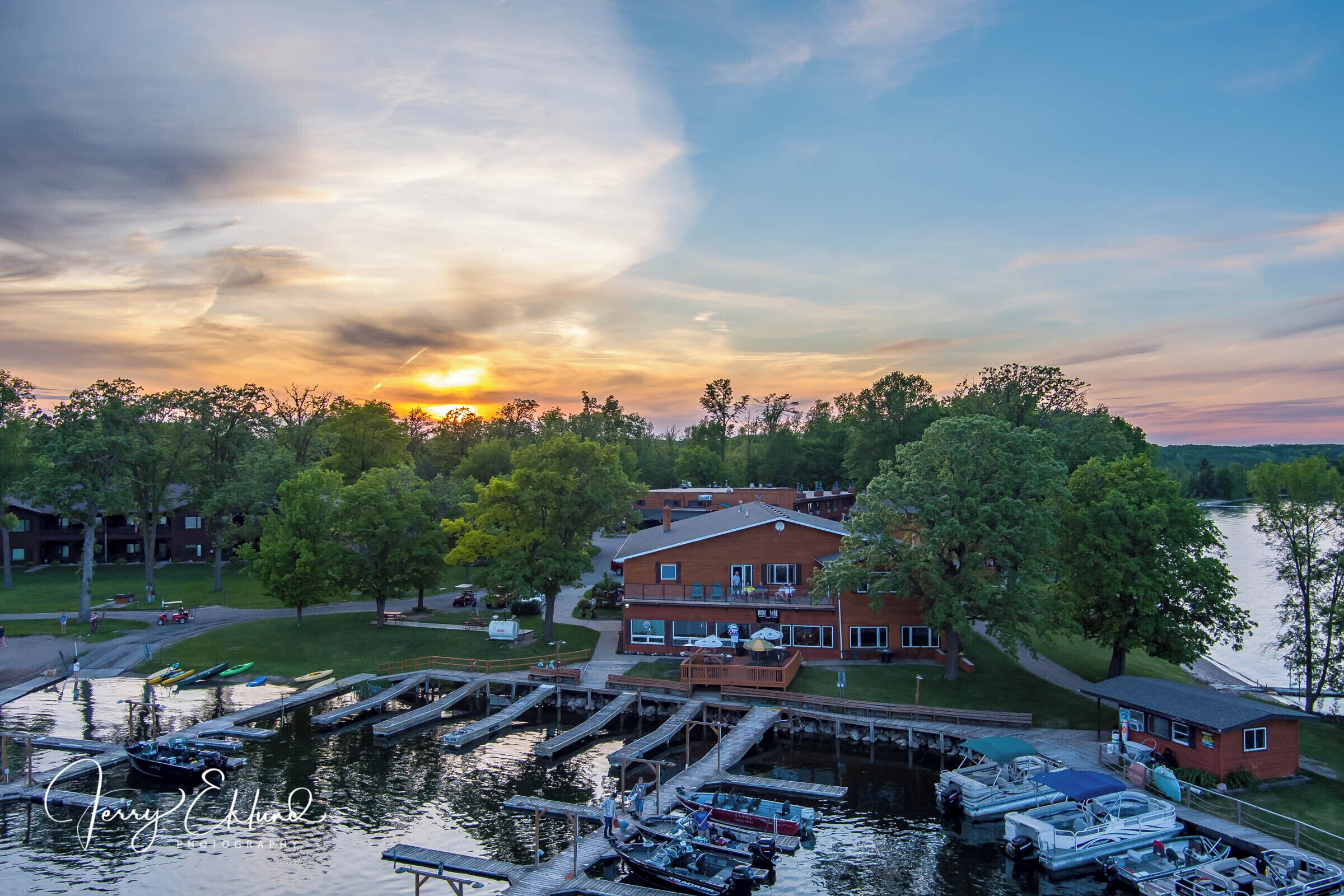 A waterfront property with a dock, boats, and a large house with a deck.