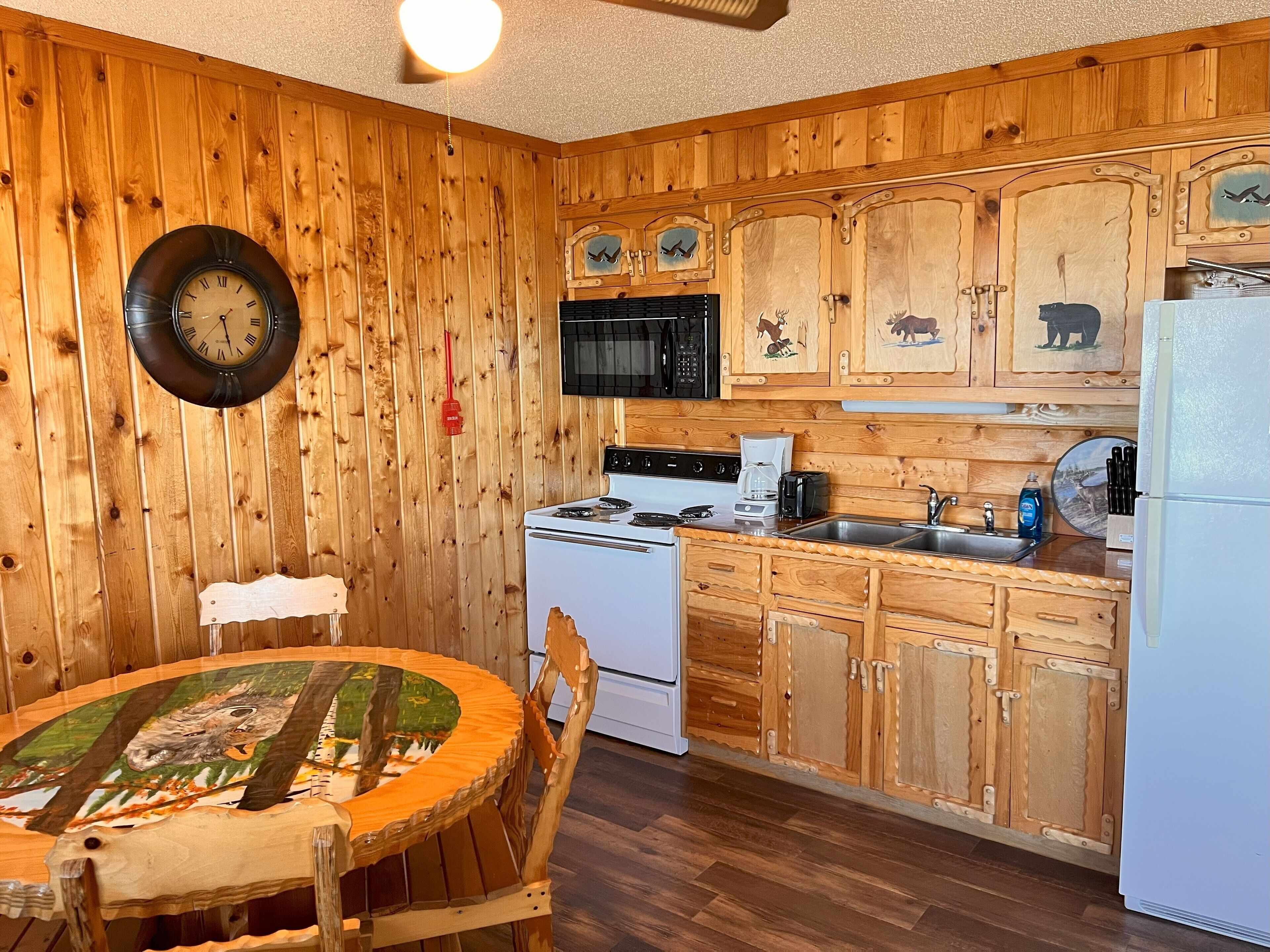 A wooden-paneled kitchen with a round table, white stove, and wooden cabinets.