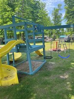Un parque infantil con tobogán, columpios y una escalera.