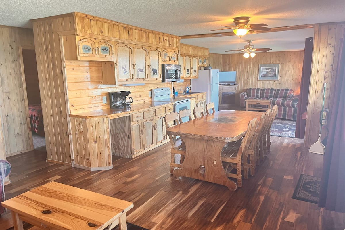 A wooden kitchen with a central island, built-in appliances, and a dining area with a bench.