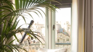 A cozy living room with a sofa, a telescope, and a potted plant. - Godó Luxury Apartment Passeig de Gracia (Barcelona)