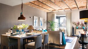 A modern dining area with a brick ceiling, a dining table set with chairs, and a view of the city through large windows. - Godó Luxury Apartment Passeig de Gracia (Barcelona)