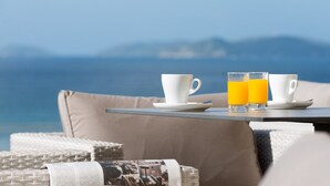 A table with two white cups and two glasses of orange juice, set against a backdrop of a mountainous landscape. - Pousada A Lanzada (O Grove)