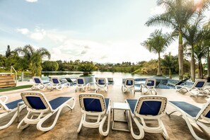 Una piscina al aire libre, sillones reclinables de piscina