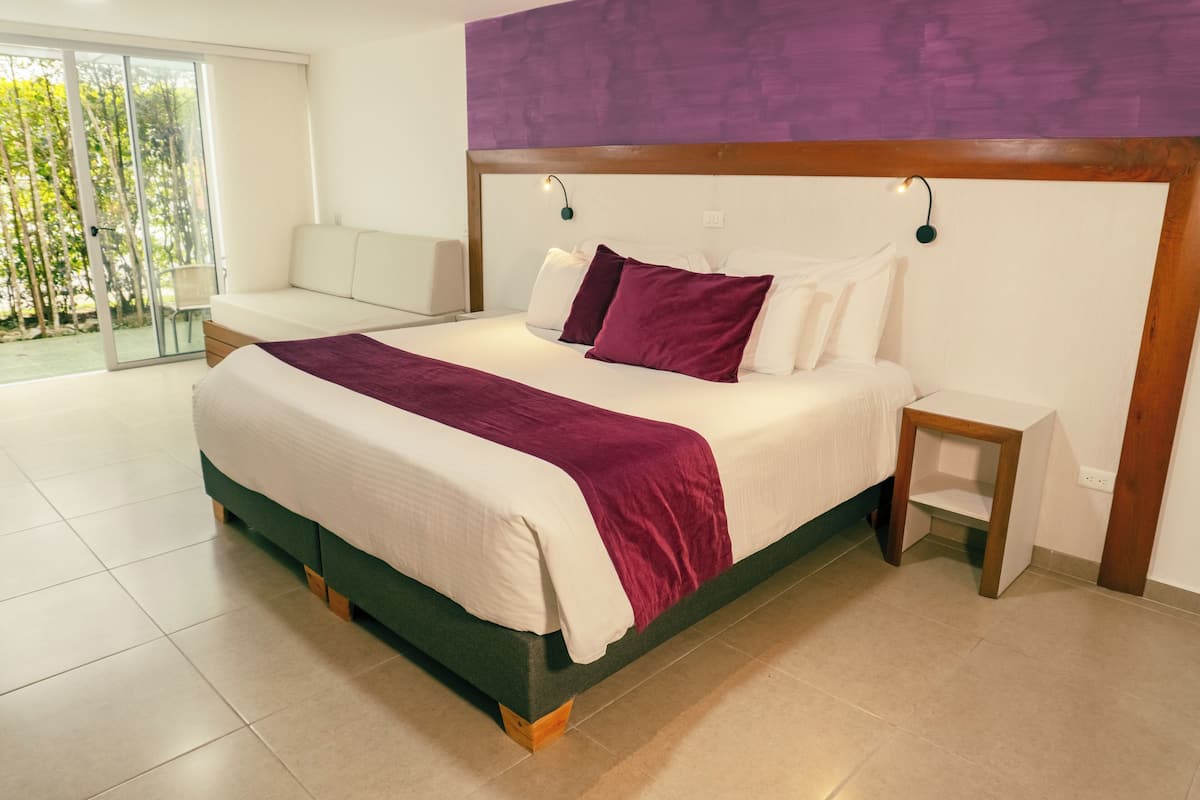 A modern bedroom with a large bed, a nightstand, and a view of a balcony.