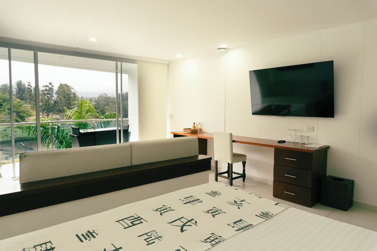 A modern room with a large window, a flat-screen TV, a desk, and a chair.