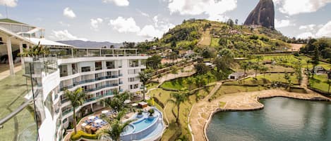 Un resort con piscina, vistas a la montaña y un edificio grande de varios pisos.