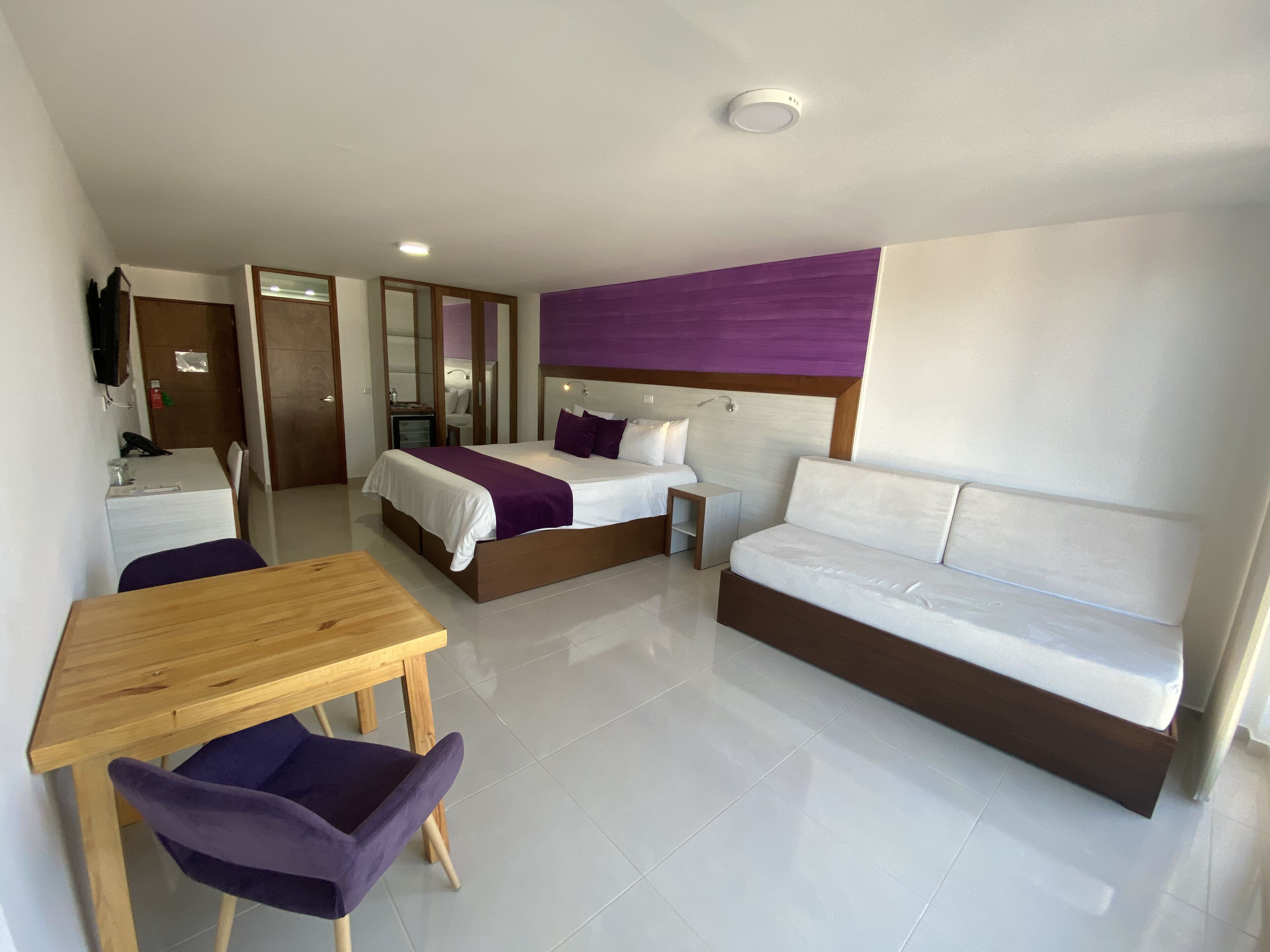 A hotel room with a bed, a sofa, a desk, and a chair.