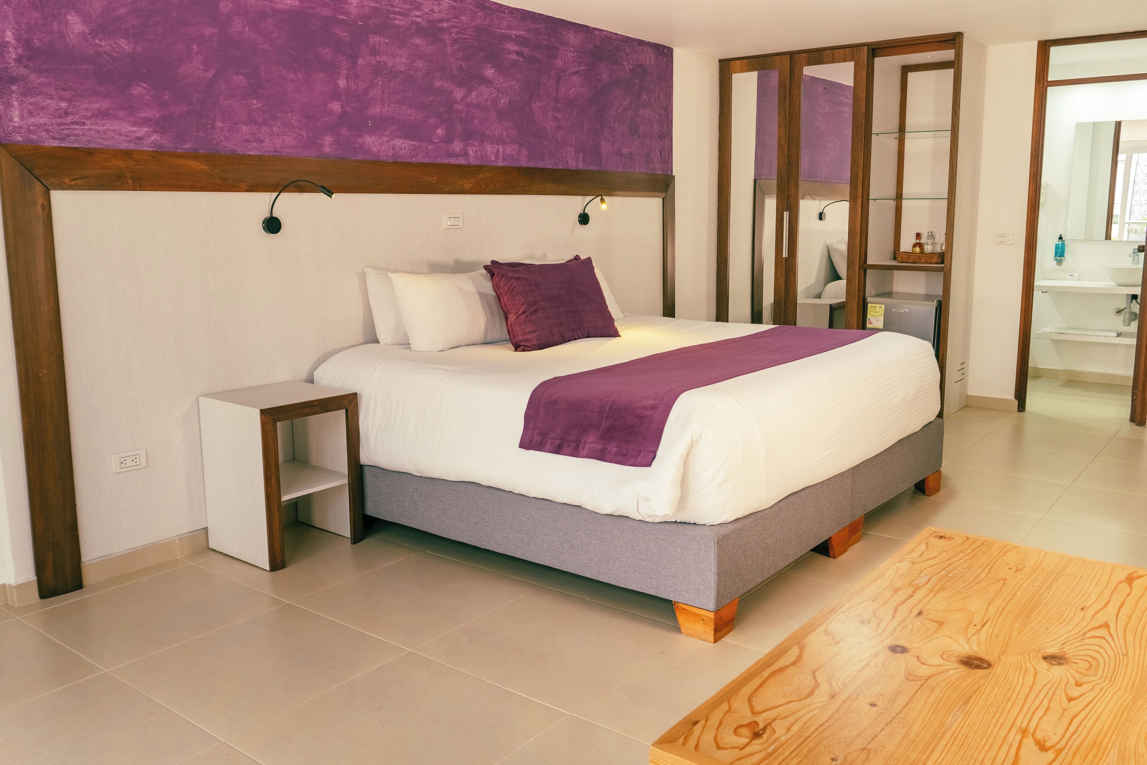 A modern bedroom with a bed, bedside table, and a wooden floor.
