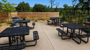 An outdoor patio area with picnic tables and benches, surrounded by a wooden fence and greenery. - Oak Ridge Inn (Plymouth)
