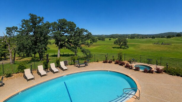 A swimming pool with lounge chairs, a hot tub, and a view of a green landscape. - Oak Ridge Inn (Plymouth)