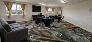 Une salle de conférence équipée d’une grande table, de chaises, d’un téléviseur et d’un tableau blanc.