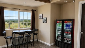 A room with a table and chairs, a window with a view, and two refrigerators stocked with beverages. - Oak Ridge Inn (Plymouth)