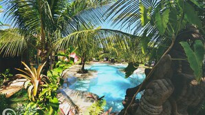 Una piscina rodeada de exuberante vegetación y una estatua de piedra.