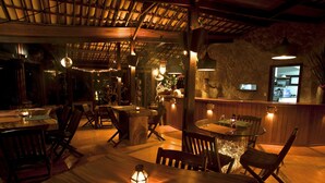 Un restaurante acogedor con mesas y sillas de madera, iluminación ambiental y un fondo de pared de piedra.