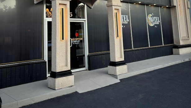A hotel entrance with a reception sign, flags, and a large sign with the hotel's name. - Motel Cofotel (Saint-Simeon)