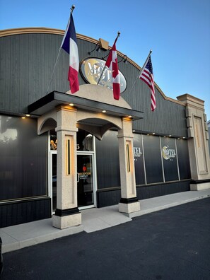 L’entrée d’un hôtel, avec un panneau indiquant la réception, des drapeaux et une grande enseigne portant le nom de l’hôtel.