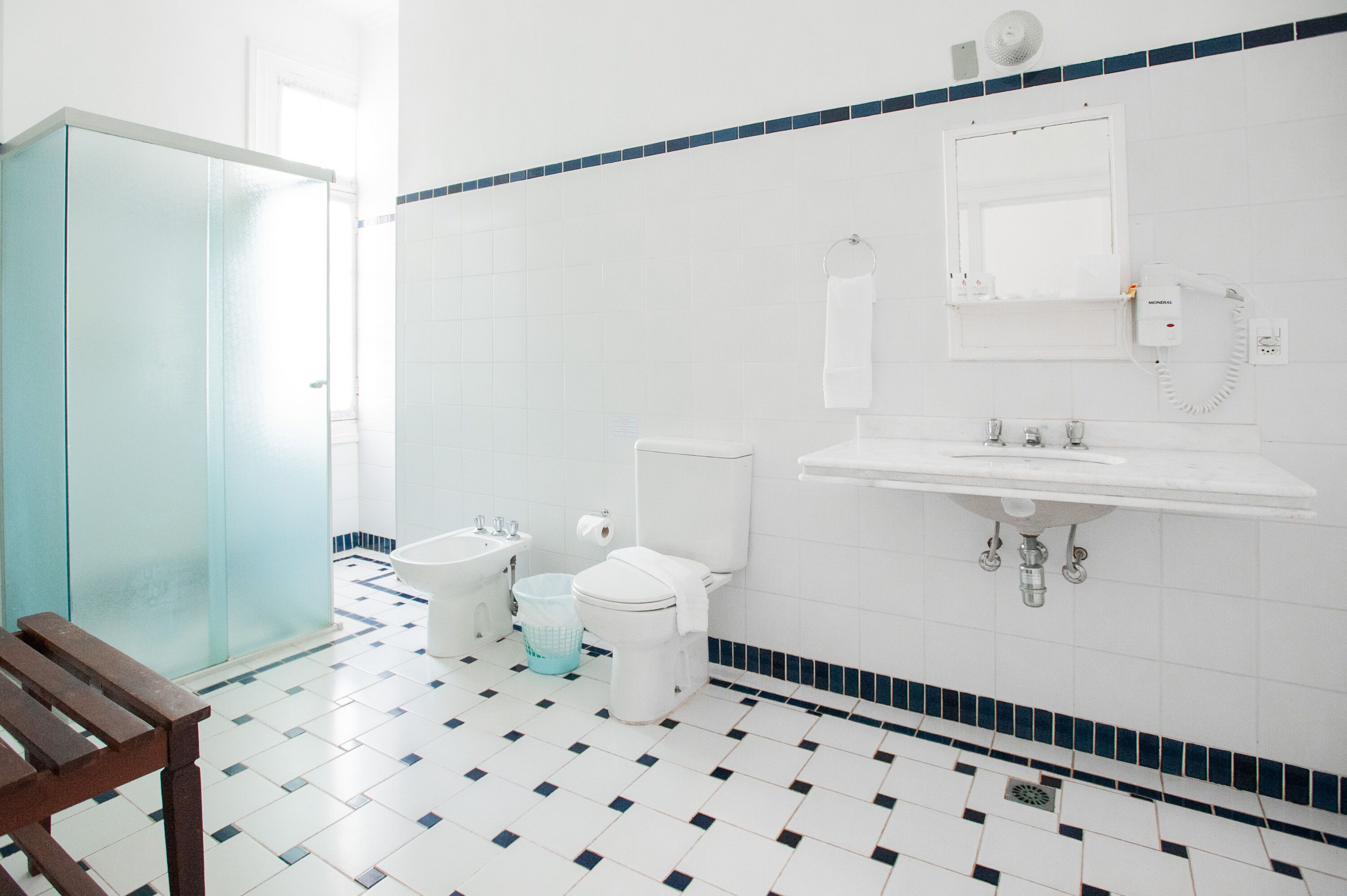A bathroom with a toilet, bidet, sink, and a mirror.