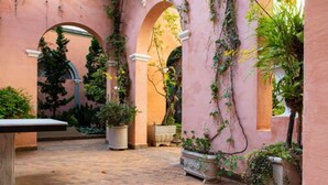 Un patio con suelo de ladrillo, arcos y plantas en macetas.