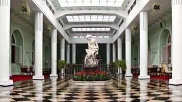A lobby with a checkered floor, a central statue, and columns.