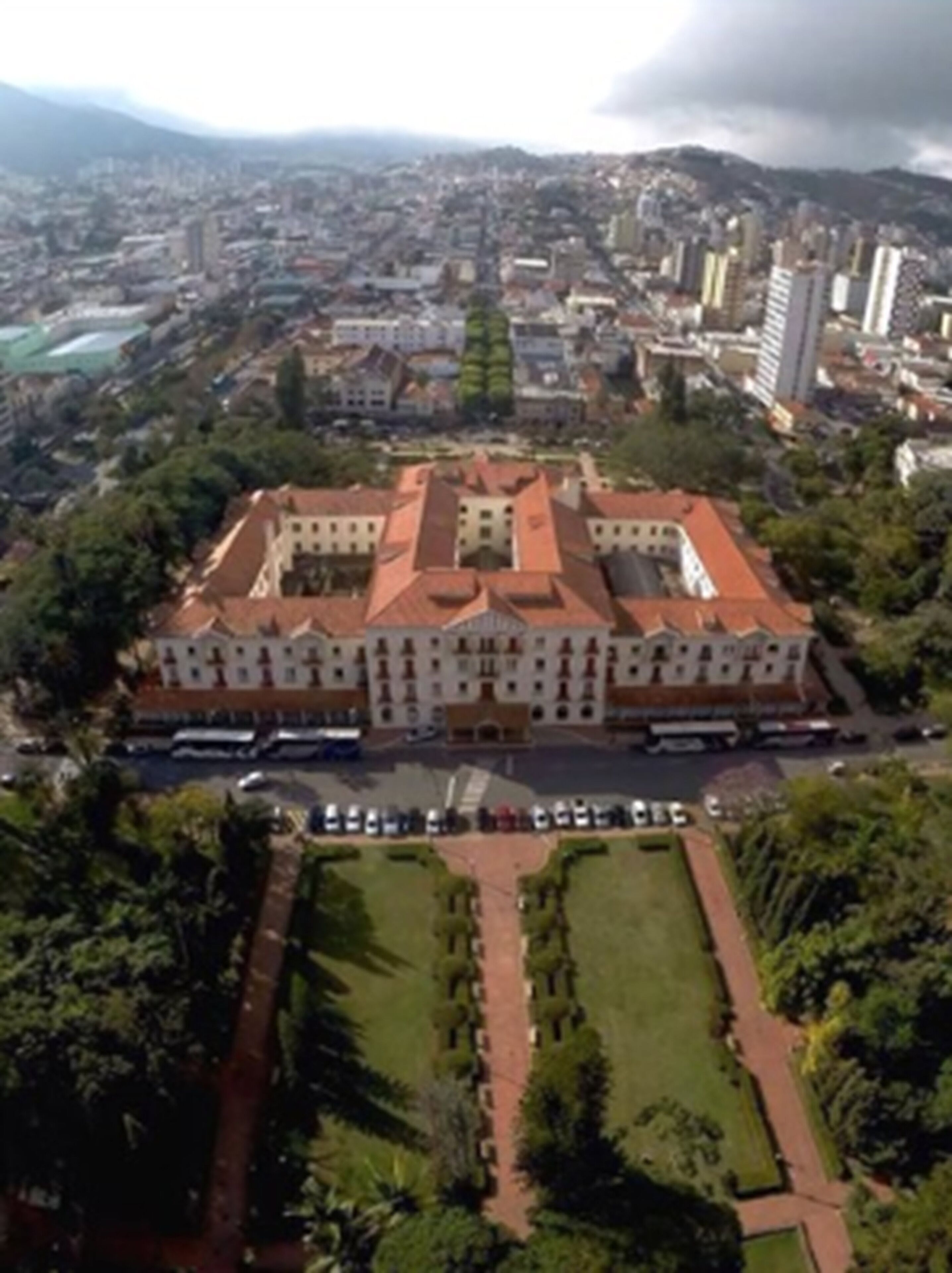 An aerial view of a large, historic building with a central courtyard and surrounding greenery.