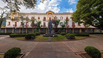 Un patio con una estatua, rodeado por un edificio con varias ventanas y balcones.