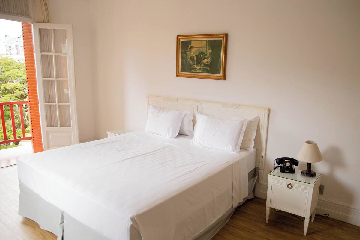 Ein Schlafzimmer mit einem großen Bett, einem Nachttisch mit Lampe und einem Bild an der Wand.
