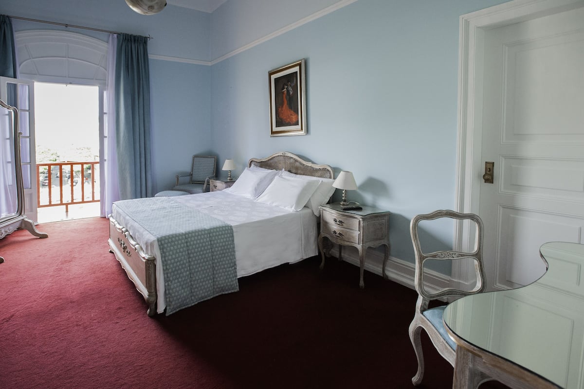 Ein Schlafzimmer mit einem großen Bett, Nachttischen, einem Sessel und einem Bild an der Wand.
