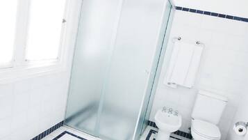A bathroom with a glass-enclosed shower, a toilet, and a sink.