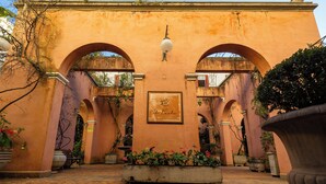 An outdoor courtyard with arches, a fountain, and potted plants. - Palace Hotel (Poços de Caldas)