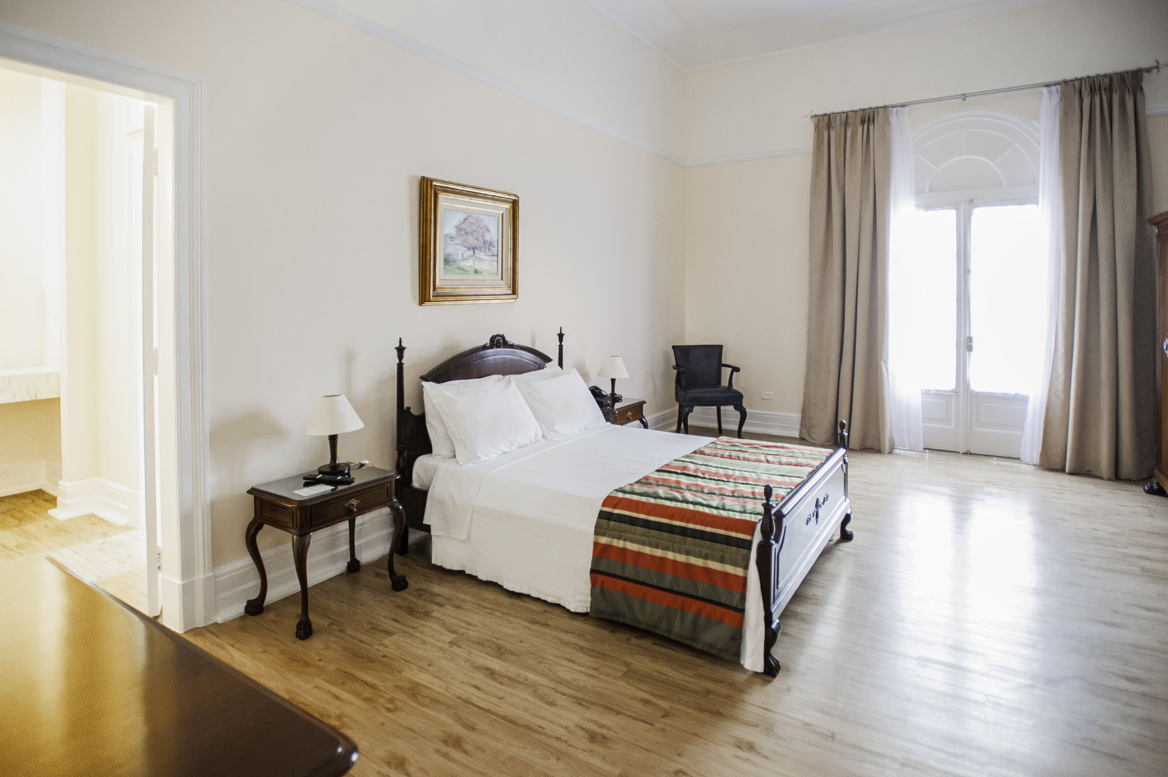 A bedroom with a bed, bedside tables, a chair, and a window with curtains.