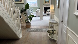 Un couloir avec un escalier, une cheminée et une vue sur le salon.