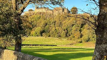 A stone wall with a grassy field and trees in the background.