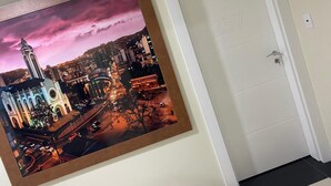 A framed cityscape photograph on a wall, a white door with a number, and a light switch.