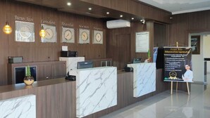 A hotel reception area with a marble counter, clocks displaying different cities, and a poster for a massage therapy service.