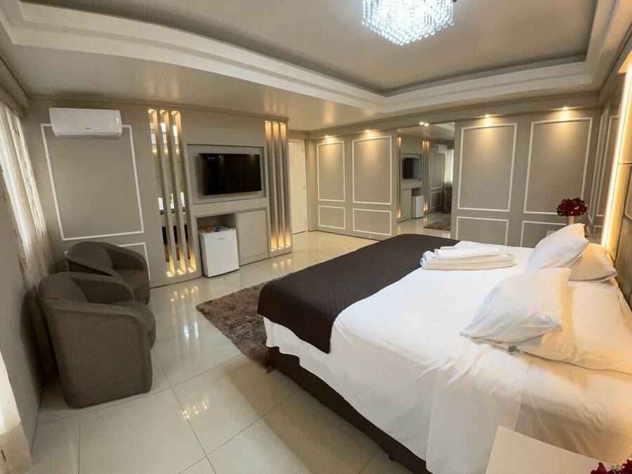 Un dormitorio moderno con una cama grande, un televisor y un área de descanso.