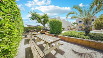 Ein Patio-Bereich mit Picknicktischen und einem Pool.