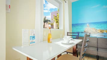 A dining area with a table, chairs, a bottle of champagne, and a menu stand.
