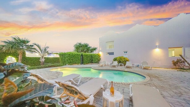 Una piscina con lettini e vista sul tramonto.