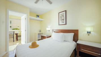 A hotel room with a bed, bedside tables, a ceiling fan, and a window with a view of the outside.