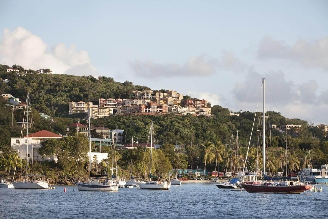Une ville côtière avec des bâtiments construits sur une colline et des bateaux amarrés dans l’eau.