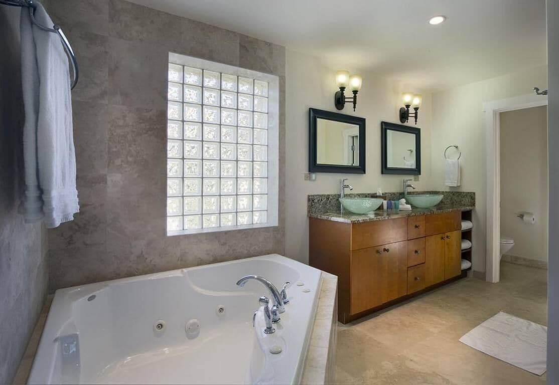 A modern bathroom with a large bathtub, two sinks, and a vanity with a mirror.