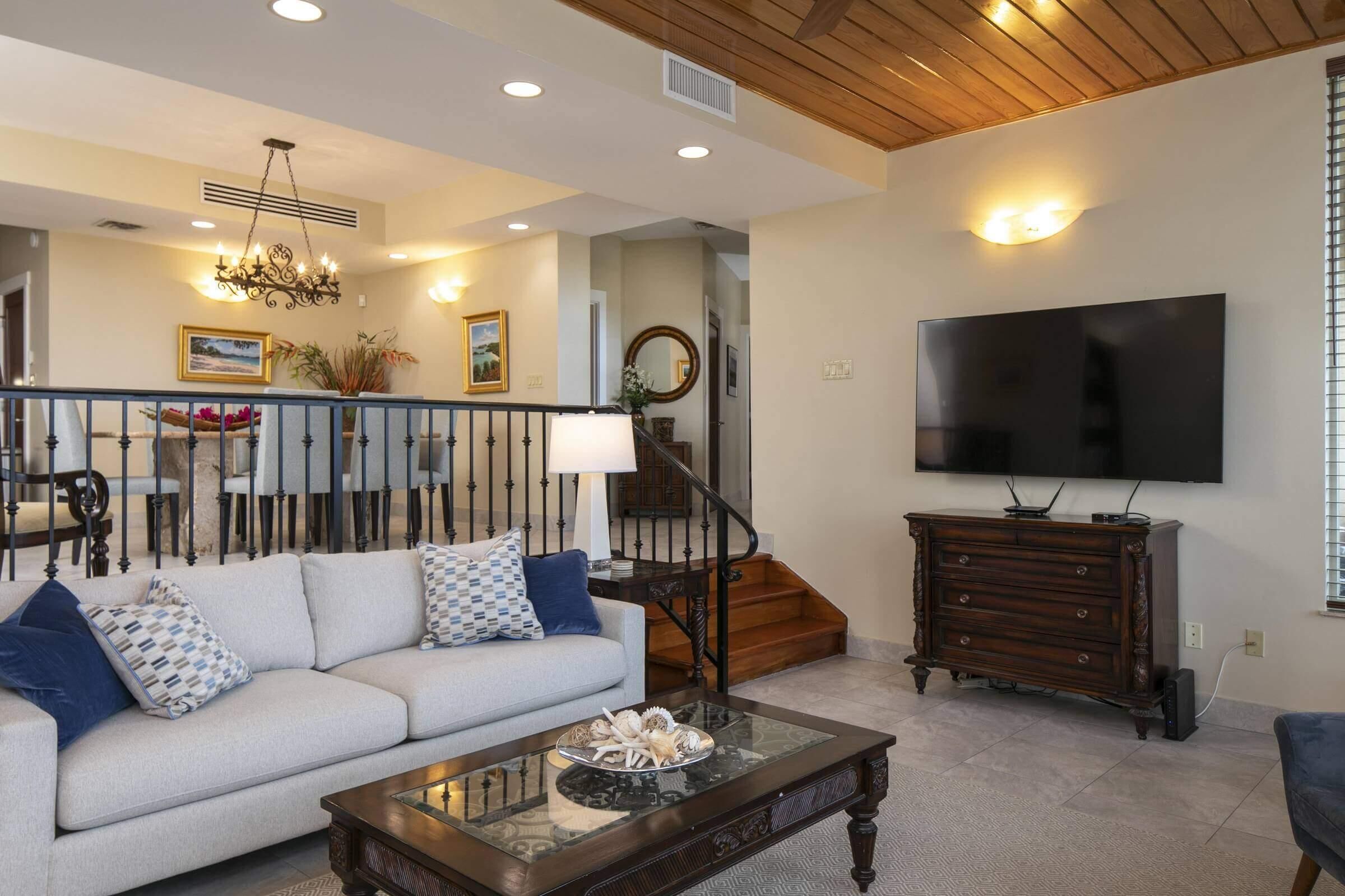 A living room with a sofa, coffee table, TV, and staircase.