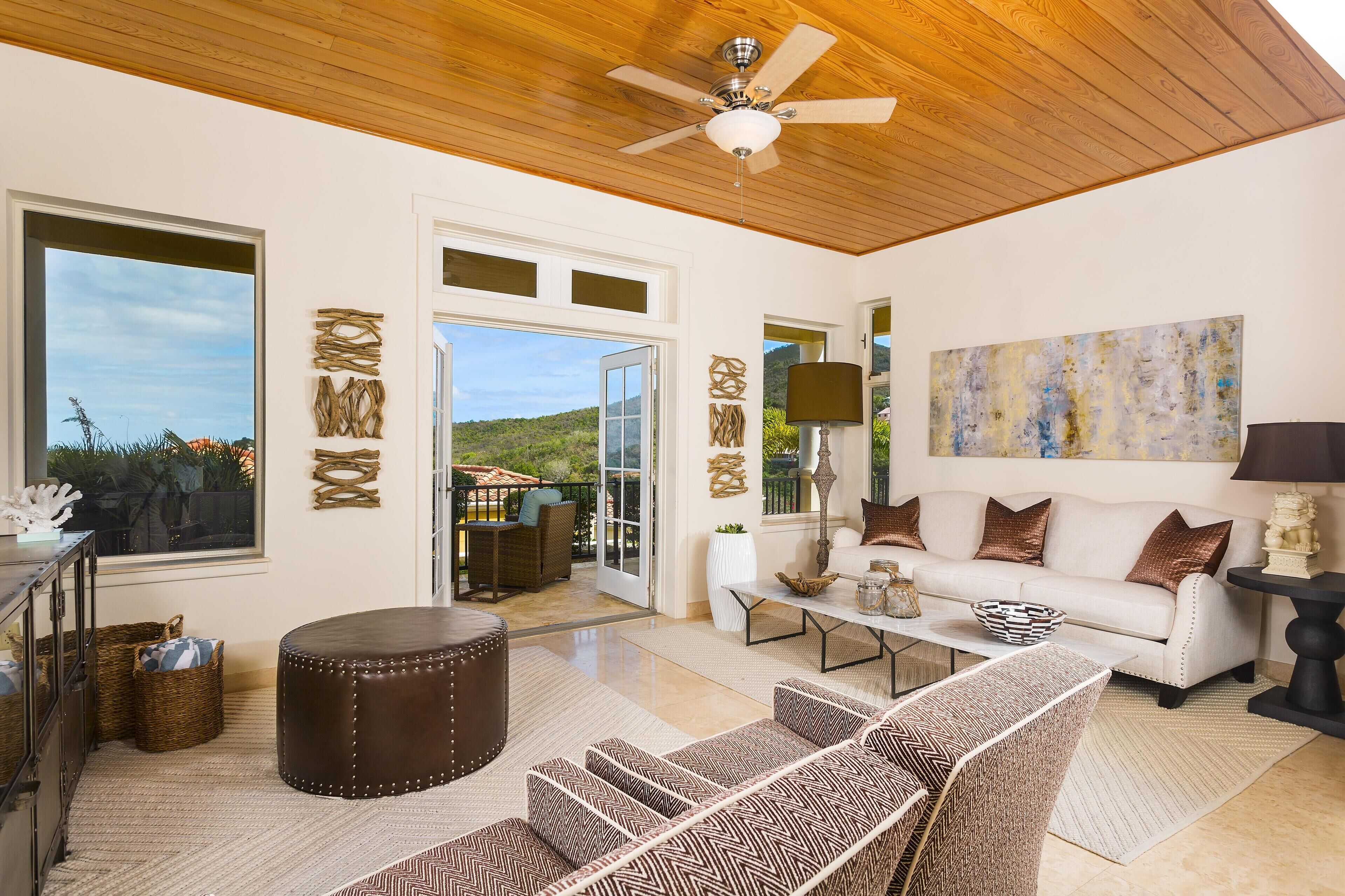 A spacious living room with a ceiling fan, a white sofa, a patterned armchair, and a coffee table.
