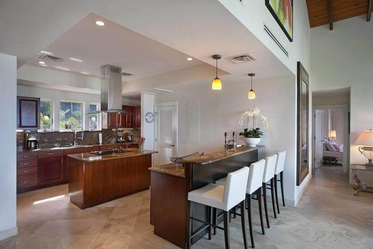 A modern kitchen with a central island, bar stools, and pendant lighting.