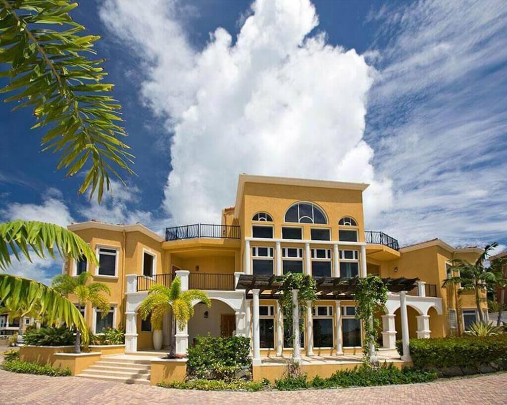 A multi-story hotel with a yellow facade, large windows, and a covered outdoor area with columns.